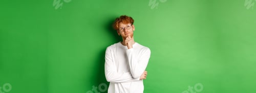 Preview: Thoughtful redhead man in glasses making choice, looking up and thinking, standing over green