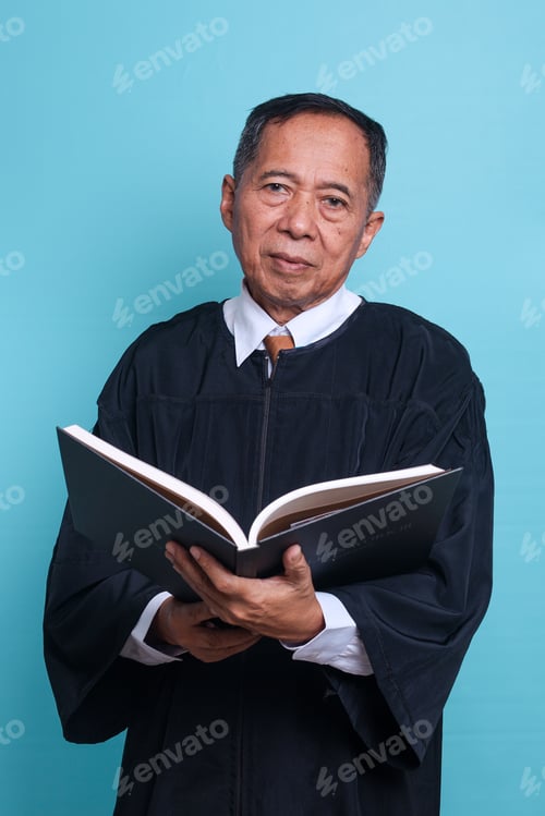 Preview: Senior judge Asian man in a gown carrying a law book