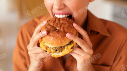 Preview: Closeup shot of hungry unrecognizable lady biting, eating tasty burger, enjoying fast food cheat
