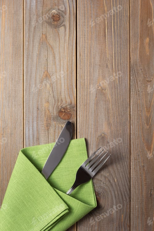 Preview: knife and fork in napkin at rustic wooden background