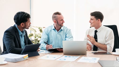 Preview: Three men are sitting at a table in a business meeting