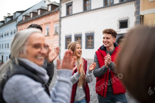Preview: Diverse group of happy community service volunteers claping hands outdoors in street