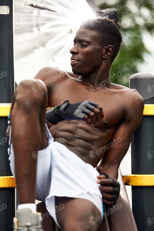 Preview: Working out in the morning. Young strong african man in sportswear exercising outdoors. Sport