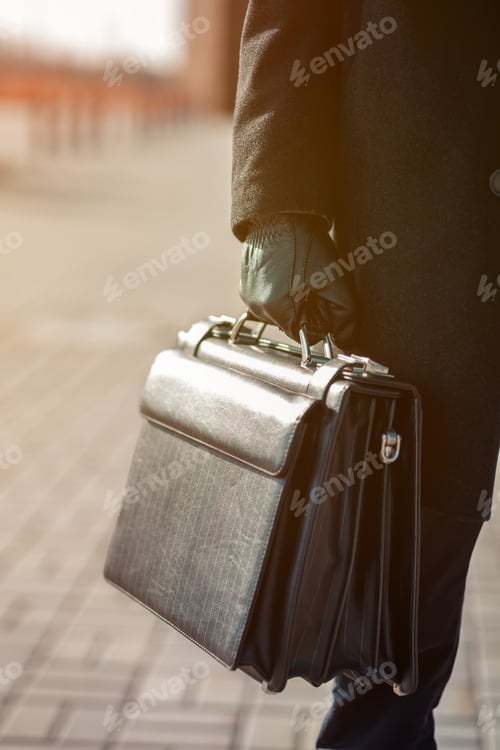 Preview: leather briefcase in his hand. young businessman walking on the street