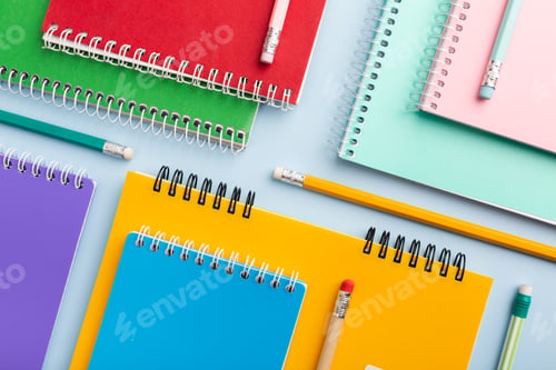 Preview: colored notebooks, colored pencils on a light table. Place for your text.