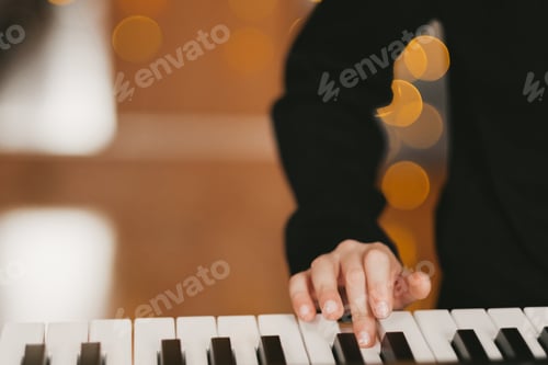 Preview: a child's hand plays the digital piano, against the background of a Christmas garland.
