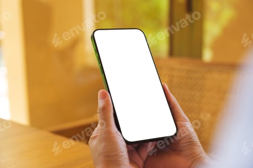 Preview: Mockup image of a woman holding and using mobile phone with blank desktop at home