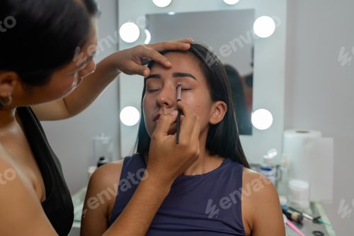 Preview: Makeup artist applying eyeshadow to young latina woman