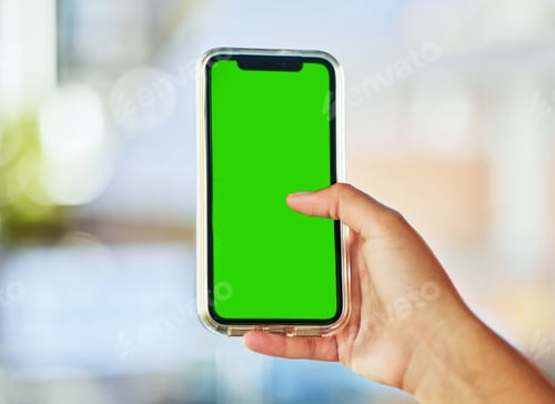 Preview: A young woman holding up a smartphone with a green screen against a defocused background.