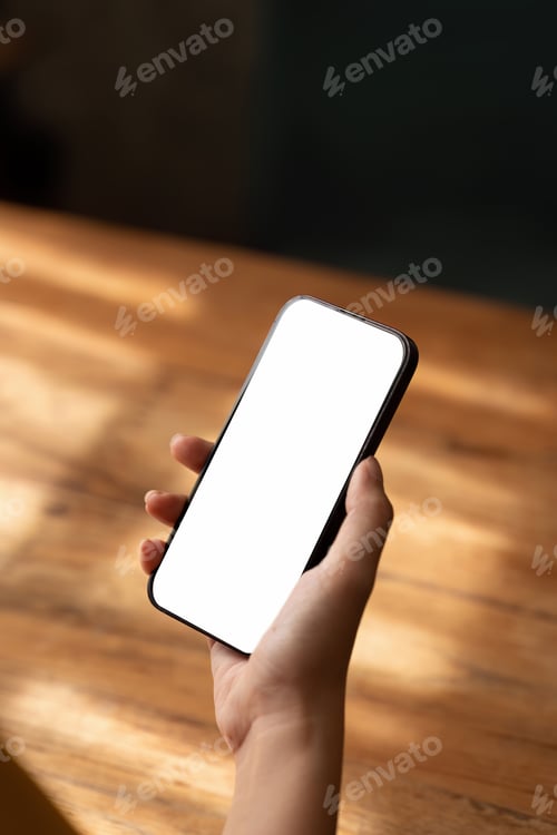 Preview: Mockup, woman's hand holding using mobile phone at coffee shop with copy space, white blank screen