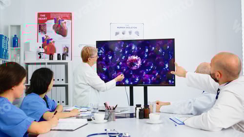 Preview: Elderly medic presenting virus evolution pointing on display in hospital office