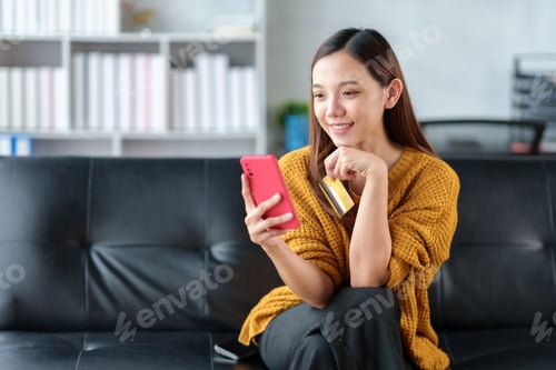 Preview: Lovely and bright Asian businesswoman conveniently shopping online on mobile using credit card