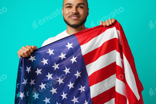 Preview: Portrait of young dark-skinned man proudly holding USA flag