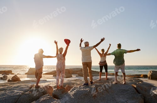 Preview: Rear View Of Senior Friends Standing On Rocks On Vacation With Arms Outstretched