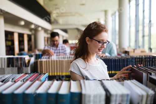 Preview: Portrait of a pretty smiling girl reading book in library