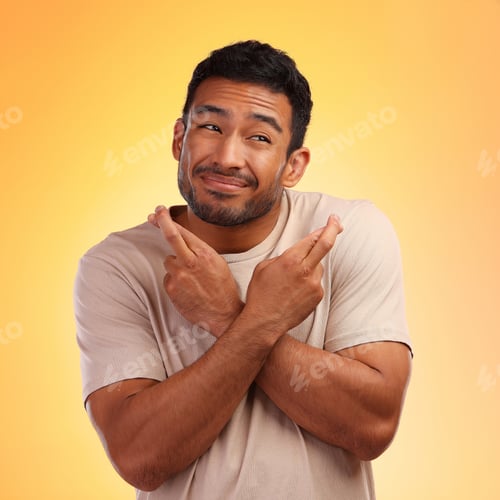 Preview: Shot of a young man crossing his fingers while standing against a yellow background