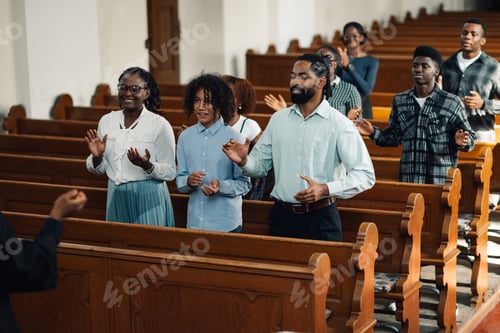 Preview: Congregation standing and praying with arms raised in church