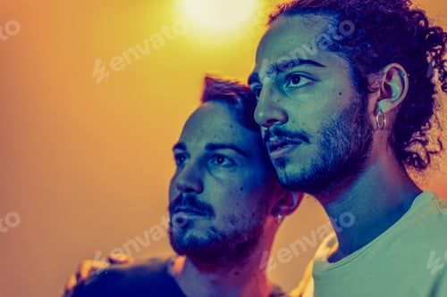 Preview: Young gay couple sharing intimate moment with colorful lighting