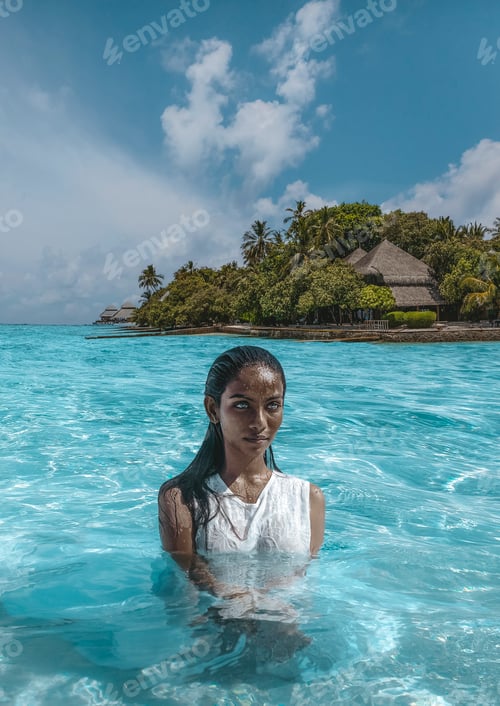 Preview: Black woman posing in crystal clear water near bungalow