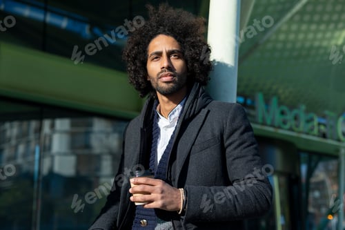 Preview: man with beard smiling positive standing at the street drinking a take away cup of coffee