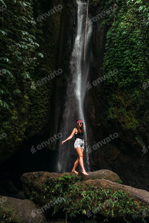 Preview: Beautiful girl at a waterfall on the island of Bali Indonesia, vertical view