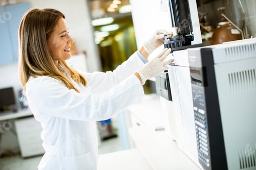 Preview: Young female scientist in a white lab coat putting vial
