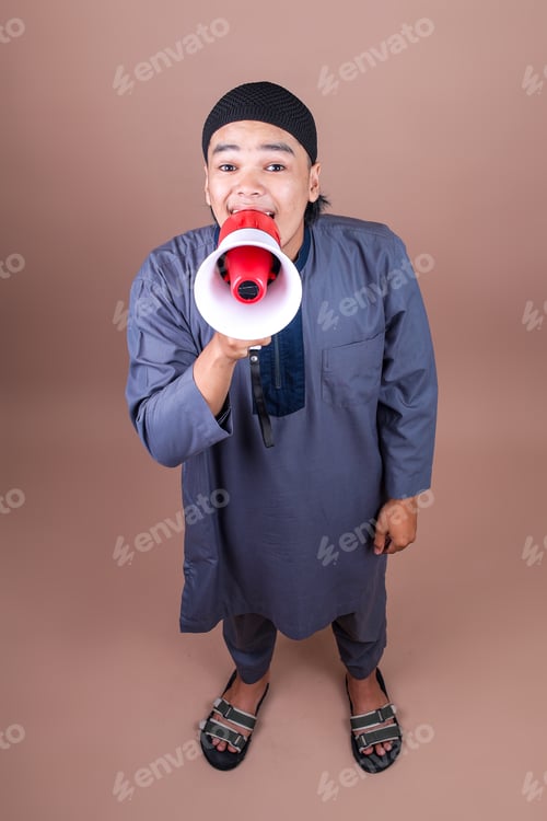 Preview: High Angle View Of Attractive Young Muslim Guy Shouting To Front Use Megaphone On Beige Studio Wall