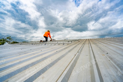Preview: Technician in safety uniform and helmet kneeling on a rooftop