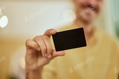 Preview: A businessman holding a credit card, showing, a close-up photo.