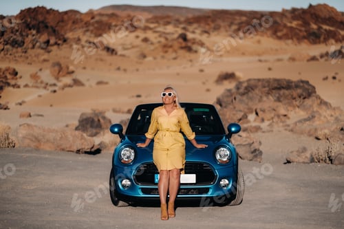 Preview: Girl in yellow dress enjoying a road trip in a convertible through a deserted valley with mountains