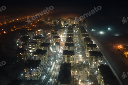 Preview: Aerial view of high rise apartment buildings and bright illuminated streets in city residential area