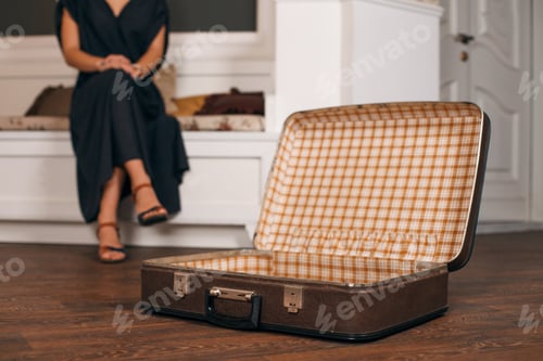 Preview: Woman sitting in front of an open suitcase .