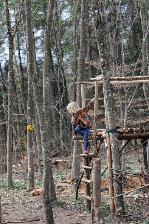 Preview: A blonde child is playing in the forest in a fort built by scouts