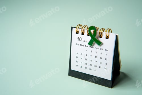 Preview: A calendar opened to the month of October and a green ribbon.