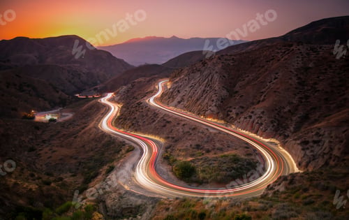 Preview: Landscape of roads on hills with long exposure car trails during a beautiful sunset