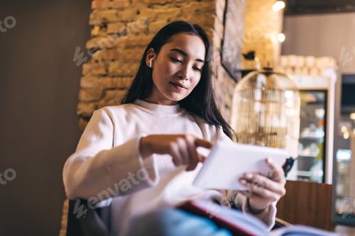 Preview: Young female in headphones enjoying music and reading social news