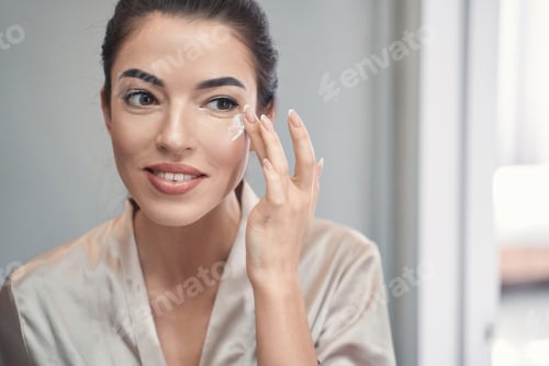 Preview: Lovely young brunette applying daily cream on her face