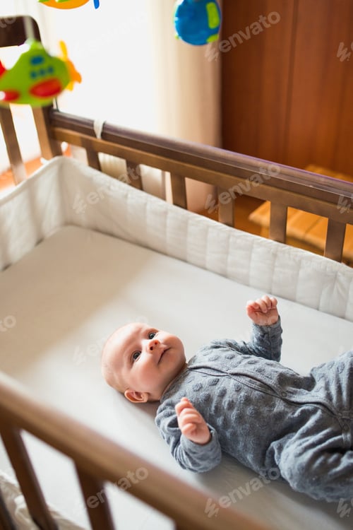 Preview: Cute little baby lying in bed and watching toys