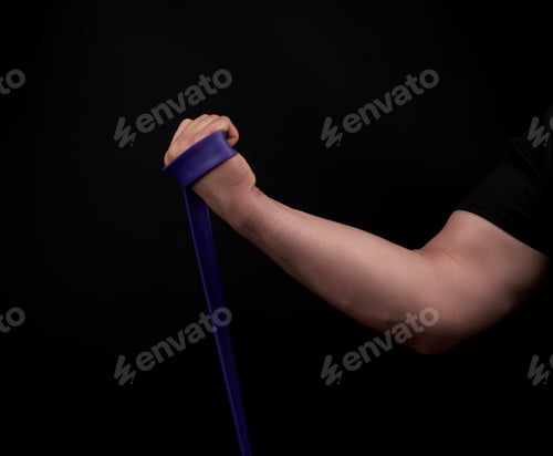 Preview: Athlete with a muscular body in black clothes is doing physical exercises with purple rubber