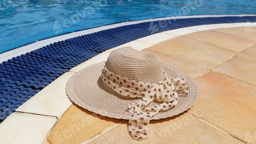 Preview: Hat with polka dot ribbon laying at the edge of the swimming pool. Summer vacation, travel concept.