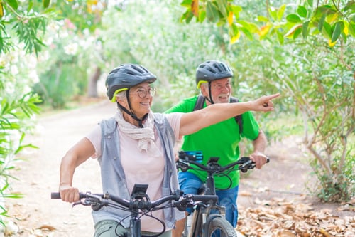 Preview: Two happy old mature people enjoying and riding bikes together to be fit and healthy outdoors.