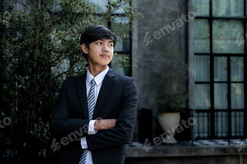 Preview: Young businessman financier investors stand with a luxurious black hotel building in the background
