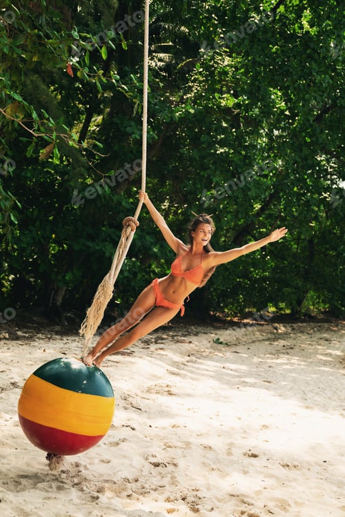 Preview: Happy woman on swings made from old buoy on the beach