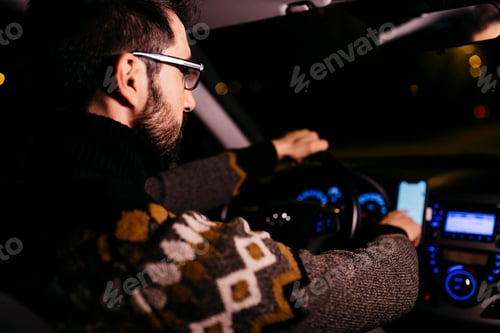 Preview: Man using cell phone with road maps in the car at night