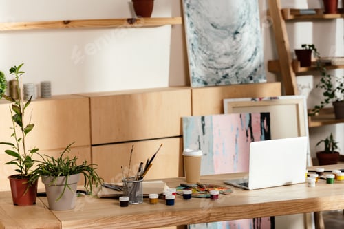 Preview: interior of artist studio with painting supplies, laptop and potted plants