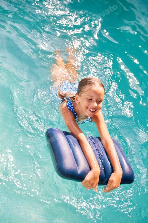 Preview: Happy little girl having fun in the swimming pool, dives and swim,