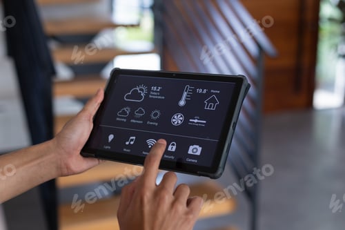 Preview: Hands of biracial man at home using tablet with smart home interface on screen