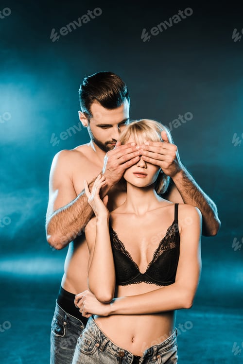 Preview: handsome boyfriend closing eyes of blonde girlfriend on blue smoky background