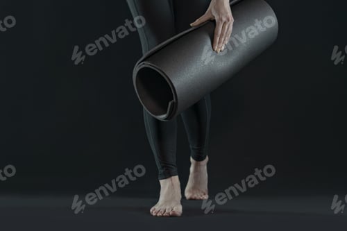 Preview: woman legs walking practicing yoga on yoga mat on a dark black background. copy space