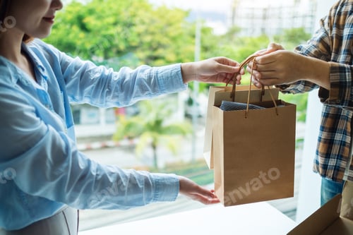 Preview: A woman receive shopping bags form delivery man at home